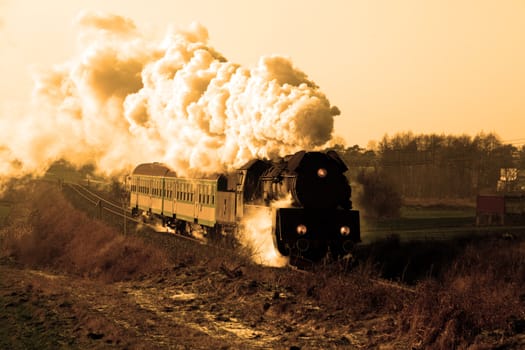 Vintage steam train passing through countryside, wintertime
