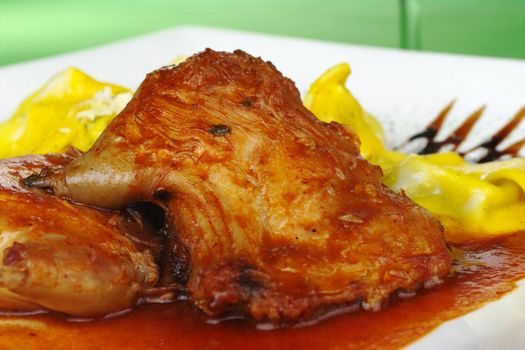 Main Dish: Guinea pig meat with gravy and tortellini on green background (Selective Focus)