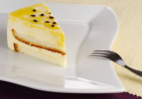 A piece of passionfruit cake on white plate with cake fork (Selective Focus)