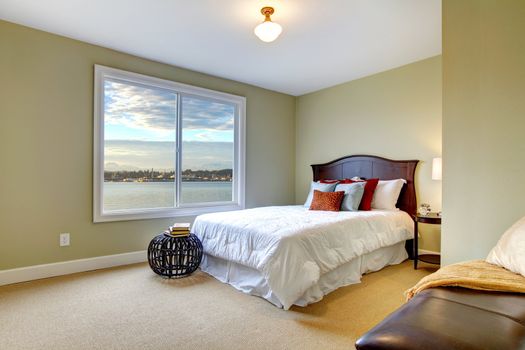 Green green bedroom with water view and white bedding.