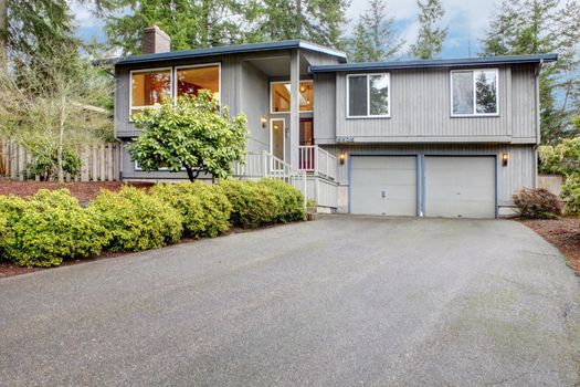 Simple grey brown split level with two garage doors.