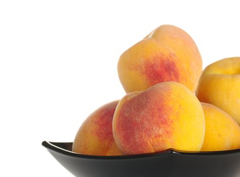 Fresh peaches in a black bowl isolated on white (Selective Focus, Focus on the peach in the front)