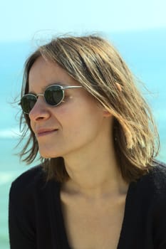 Portrait of a young woman in sunglasses on the coast (Selective Focus, Focus on the left side of the face)