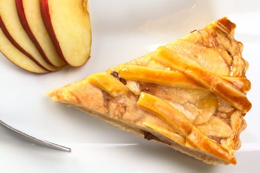 A slice of delicious apple pie with apple slices and fork photographed from above (Selective Focus, Focus on the top of the apple pie)