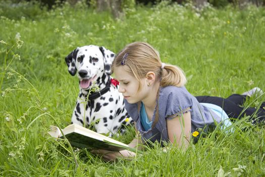 A little girl reading a book outdoor, warm spring day