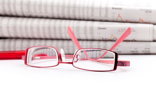 reading glasses lie before a big newspaper pile