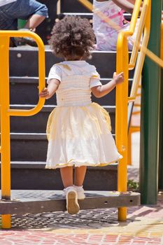A little girl climbing up the stairs in a playground