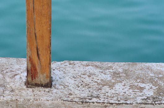 Brown wooden post sunk into a cement wall