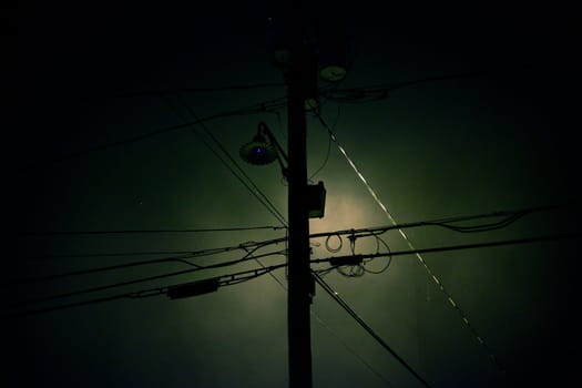 Telephone pole and wires silhouetted against the moon