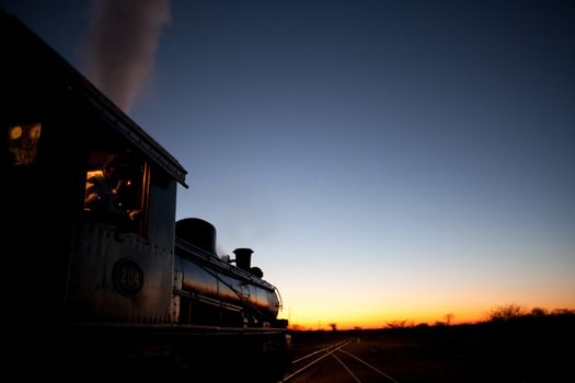 Vintage steam locomotive pointed into the sunset
