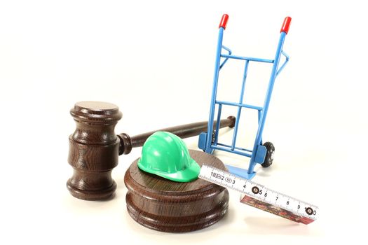 judges gavel with building-site helmet and double meter stick on a light background