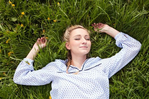 young woman lying in green gras happy