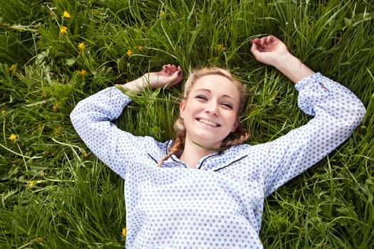 young woman lying in green gras happy