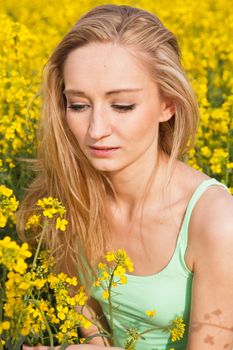 young beautiful blonde girl in a field in summer happy