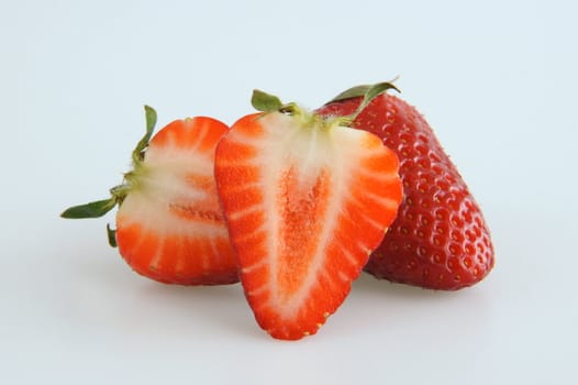 Image of two isolated strawberries, one of them is sliced in half