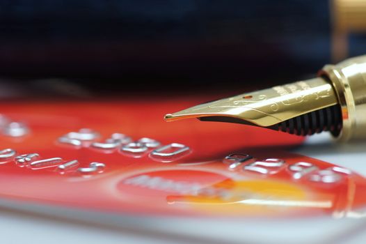 A nib of a Fountain pen over a credit card with shallow depth of field.
