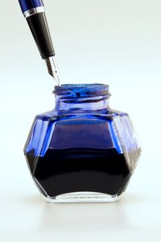 A fountain pen with blue inkwell