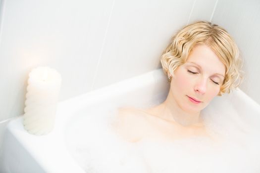 Young woman relaxing in the bath with candlelight