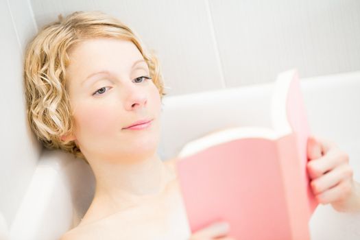 Young woman reading a book in the bath