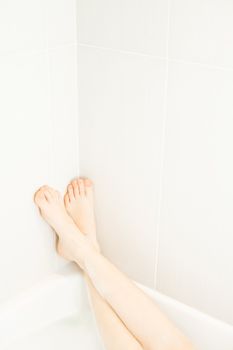 Woman legs in the corner of the bath with bubbles