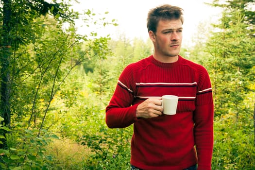 Man lost in nature with a mug of coffee