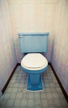 Blue flush toilet in a little vintage restroom