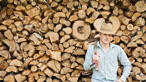 Woodcutter with straw hat on a background of wood