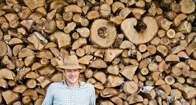 Woodcutter with straw hat on a background of wood taking a little break