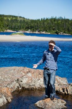 Young man lost and standing on a rock in the middle of the water