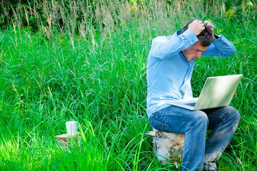 Despair man outdoors with a cup and laptop