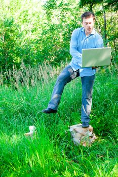 Young man outdoors with a cup and laptop doing acrobatic pose