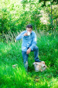A young businessman in nature with a mug