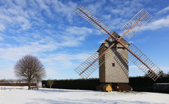 Countryside landscape with traditional windmill during the winter, located in the central part of France.