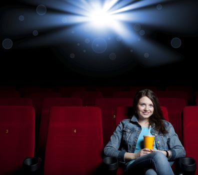 beautiful woman in a movie theater, watching a movie and drink a drink