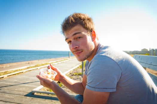 Young man eating seafood on the beach