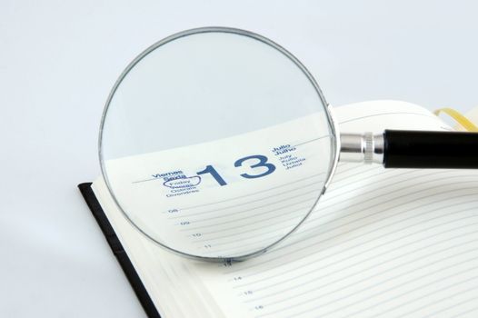 A magnifying glass  focusing a friday 13 in a agenda