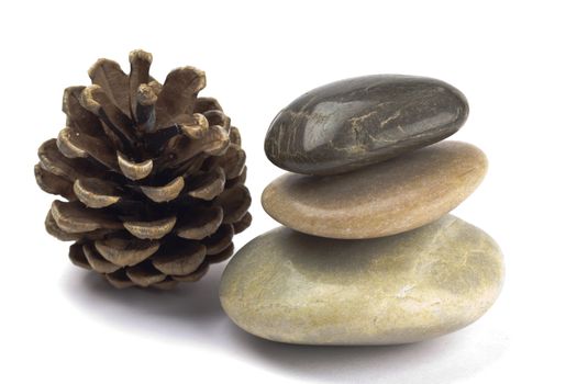 Shiny smooth pebbles in a stack with a pine cone