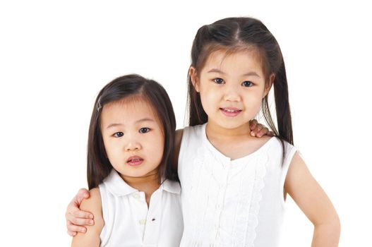 Asian sisters arms around on plain background