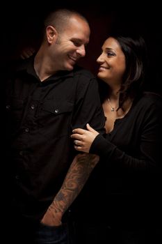 Happy Mixed Race Couple Flirting with Each Other Portrait Against A Black Background.