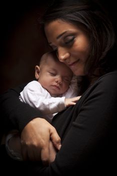 Young Attractive Ethnic Woman Holding Her Newborn Baby Under Dramatic Lighting.