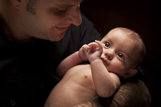 Happy Young Father Holding His Mixed Race Newborn Baby Under Dramatic Lighting.