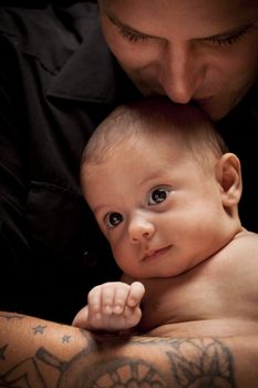 Happy Young Father Holding His Mixed Race Newborn Baby Under Dramatic Lighting.