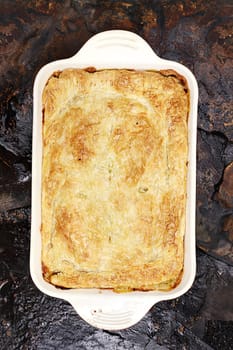 Above view of fresh Chicken Pot Pie over a rustic background.

