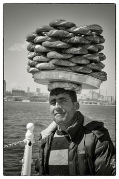 SIMIT VENDOR BOSPHORUS, ISTANBUL, TURKEY, APRIL 16, 2012: Simit vendor walking along the Bosphorus with his goods on his head trying to sell the crispy rings.