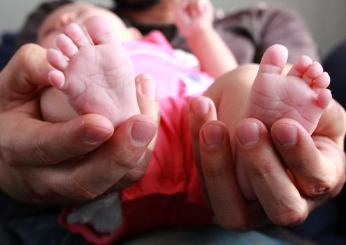 Father holding newborn sweet child feet