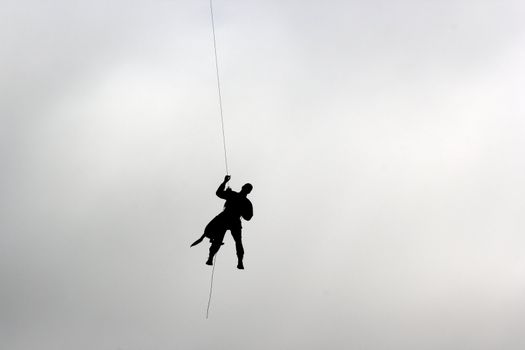 man and dog climbing down from a helicopter