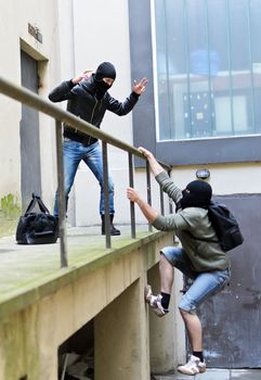 Escape from a robbery. One tries to help another to climb the rails.