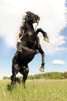 young man and her beautiful black stallion rearing up