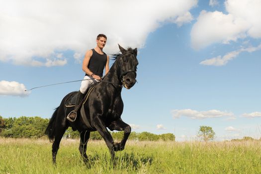 young man and his black stallion in  a field