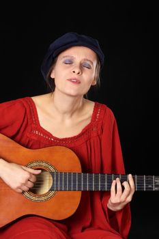 Young Caucasian woman singing and playing the guitar with eyes closed (Selective Focus, Focus on the face)